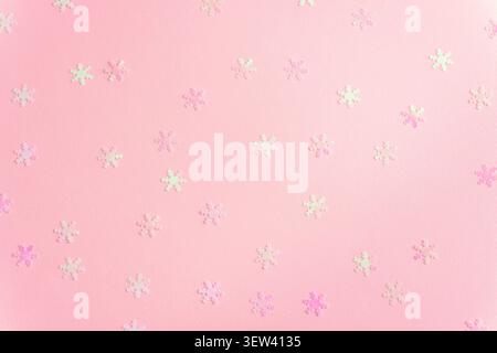 Pink background with iridescent snowflake confetti scattered in a festive winter pattern with soft pastel tones, copy space. Stock Photo