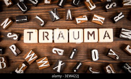Trauma Text Displayed on Wooden Blocks Surrounded by Letters Stock Photo