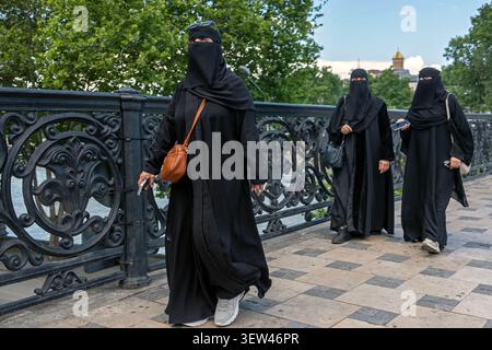 Three women wearing black niqabs walk along Metekhi Bridge in Old Town Tbilisi, Georgia. Stock Photo