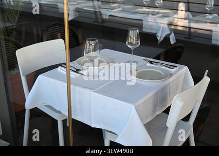 Elegantly Set Restaurant Table with White Tablecloth, Cutlery and Wine Glasses Ready for Guests Stock Photo