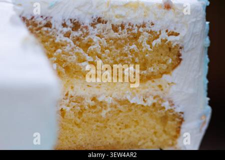 Close-up of a sliced vanilla layer cake with white frosting. Delicious sponge cake texture visible between creamy layers of sweet buttercream. Stock Photo