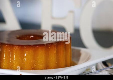 Traditional Portuguese egg pudding with caramel sauce. Delicious cream caramel flan cake served on a plate with a soft blurred white background. Stock Photo