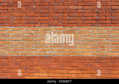 red brick wall with a lighter horizontal band across the centre Stock Photo