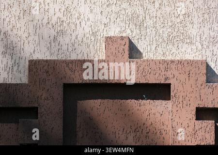 Sunlight casts shadows on a textured wall displaying geometric forms and colors. Stock Photo
