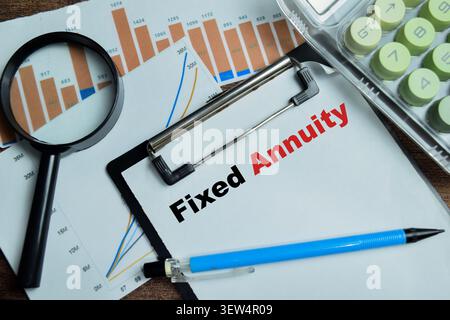 Concept of fixed annuity write on clipboard isolated on Wooden Table. Stock Photo