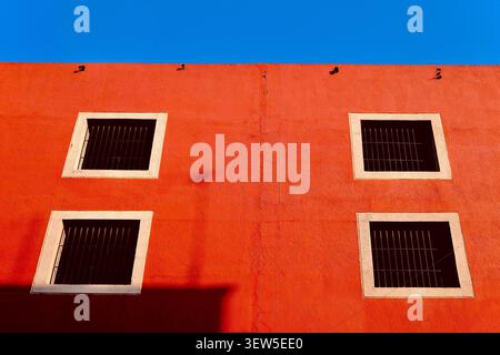 Minimalist Red Wall with Four Barred Windows (Puebla, Mexico) Stock Photo
