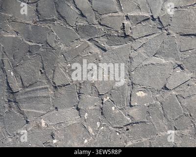 The stone paving is made of gray, broken flagstone. The uneven surface is laid out with random, flat, differently shaped fragments. Rough cement joint Stock Photo