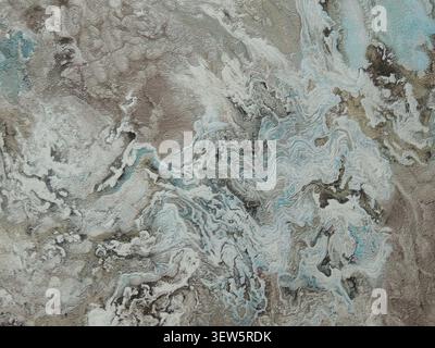 An abstract texture, simulating liquid marble or decorative plaster. Raised waves in white, beige, and gray are complemented by turquoise accents Stock Photo