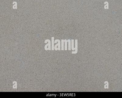 A fine-grained matte texture in a gray-beige color. The uniform, rough surface resembles polished concrete, granite chips, or plaster Stock Photo