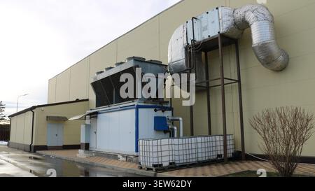 A large-scale industrial air conditioning unit, located outdoors, close to the building's blank wall. In the foreground is the main process station Stock Photo