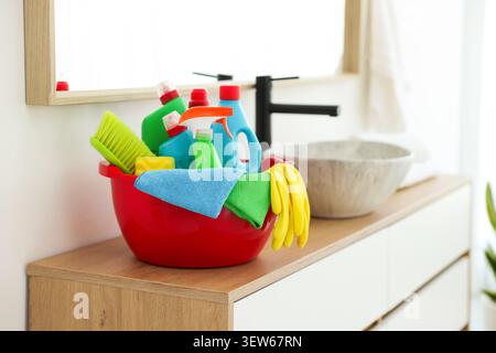 Red plastic basin with cleaning products and supplies on counter in bathroom Stock Photo