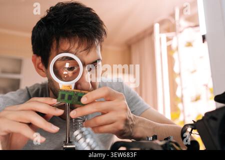 Technician using magnifying glass to inspect computer ram module, focusing on small details of circuit board for repair, technology review. Concept of Stock Photo