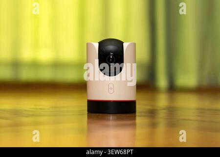 Modern indoor wireless IP security camera with 360 degree pan tilt on a wooden table. Smart home surveillance system for baby monitoring and pet track Stock Photo