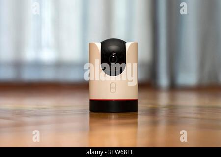 Modern indoor wireless IP security camera with 360 degree pan tilt on a wooden table. Smart home surveillance system for baby monitoring and pet track Stock Photo