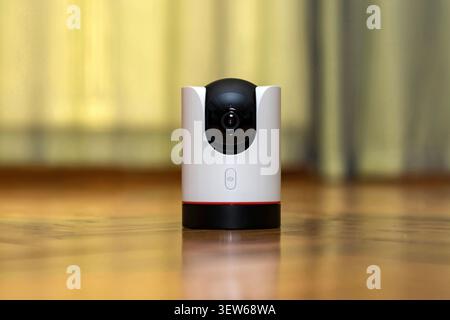 Modern indoor wireless IP security camera with 360 degree pan tilt on a wooden table. Smart home surveillance system for baby monitoring and pet track Stock Photo