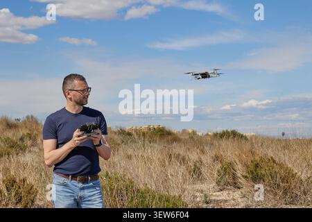 A handsome man controls a quadcopter in a field Stock Photo