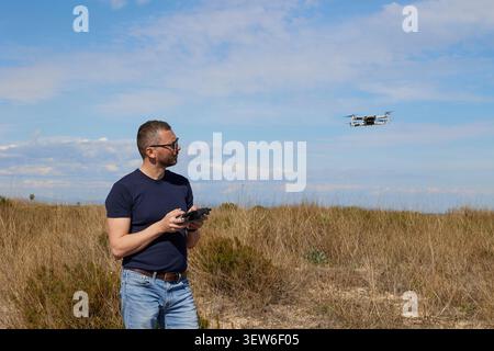 A handsome man controls a quadcopter in a field Stock Photo