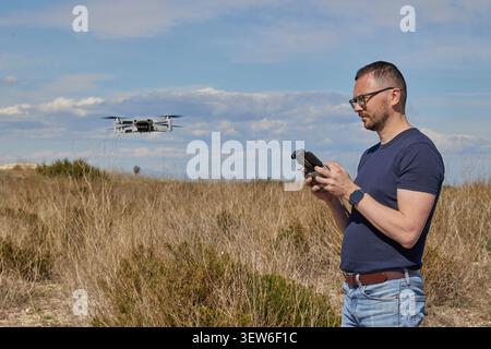 A handsome man controls a quadcopter in a field Stock Photo