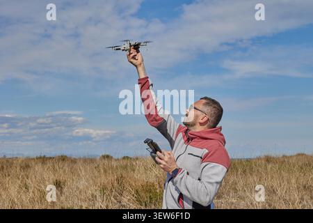 A man holds a drone on an outstretched hand field Stock Photo
