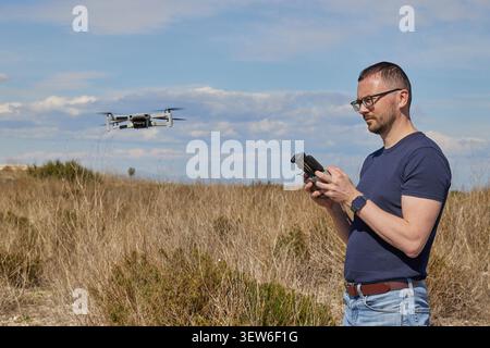 A handsome man controls a quadcopter in a field Stock Photo