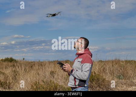 A handsome man controls a quadcopter in a field. Stock Photo