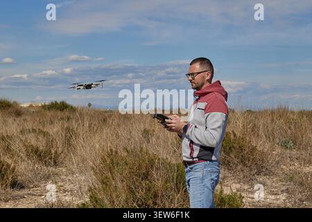 A handsome man controls a quadcopter in a field Stock Photo