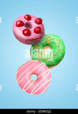 Yummy donuts covered with icing falling on light blue background Stock Photo