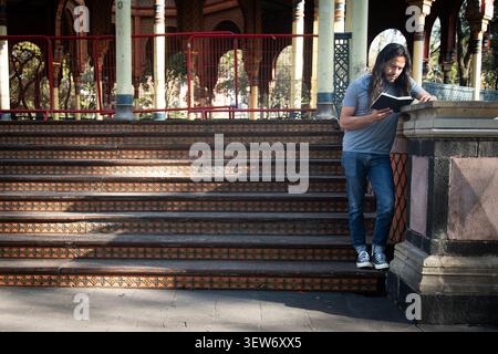 Long-haired man reading book at kiosco morisco Stock Photo