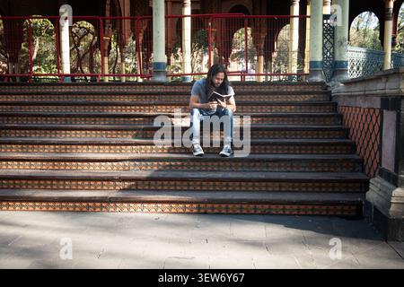 Young man reading book on morisco kiosk steps Stock Photo