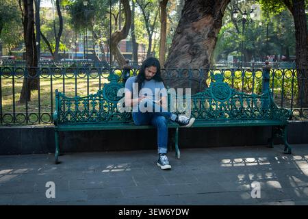 Young man reading book relaxing on park bench Stock Photo