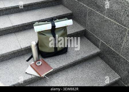 Backpack with travel essentials on stone stairs Stock Photo