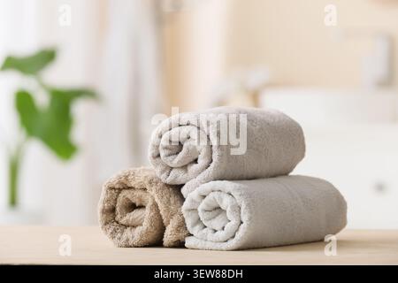 Stack of rolled beige and gray towels on wooden surface Stock Photo