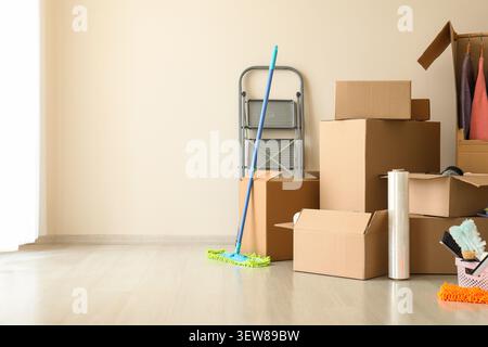 Packed cardboard boxes and cleaning supplies in empty room Stock Photo