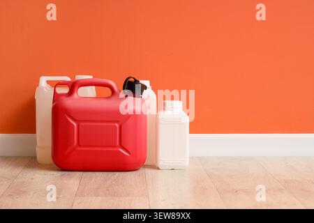 Plastic fuel and chemical containers on floor by orange wall Stock Photo