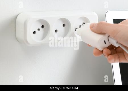 Hand plugging charger into wall socket Stock Photo