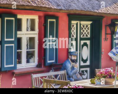 Thatched-roof house colorful door and window with sailor on bench Darss Baltic Sea Germany Stock Photo