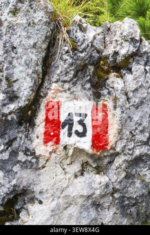 Red and white hiking trail marker sign number 13 painted on textured alpine rock face route navigation signpost Dolomites Alps Italy Stock Photo