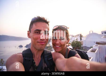 Happy couple taking selfie enjoying sunset in Santorini Stock Photo