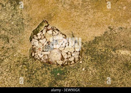 damaged concrete floor with exposed gravel background, broken gray cement surface revealing internal stones, top view of building maintenance Stock Photo
