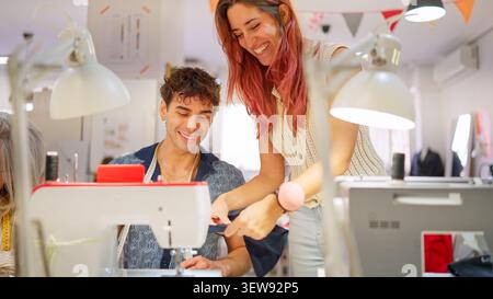 Instructors guiding student learning sewing machine in workshop Stock Photo