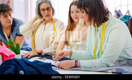 Tailor instructing students crafting fabric in sewing workshop class Stock Photo