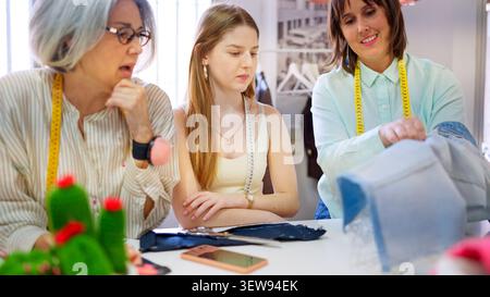 Women learning dressmaking working together in sewing workshop Stock Photo