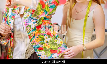 Designer fitting floral garment on customer in creative workshop Stock Photo