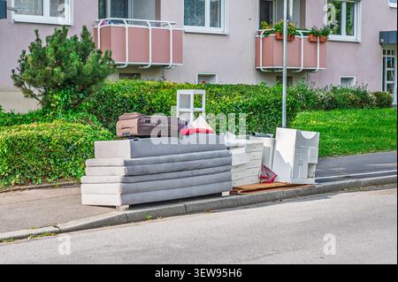 Old furniture cushions drawers and suitcase placed on a curb for bulky waste collection. Stock Photo