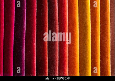Macro texture of colorful velvet fabric folded in vertical pleats showing a warm color gradient Stock Photo
