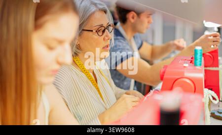 Adults learning sewing skills in textile workshop Stock Photo