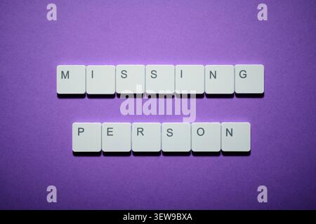 Missing person text written witk white keys of a keyboard on a purple table Stock Photo