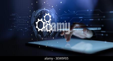Hand interacting with a digital interface featuring gear icons representing automation and workflow processes Stock Photo