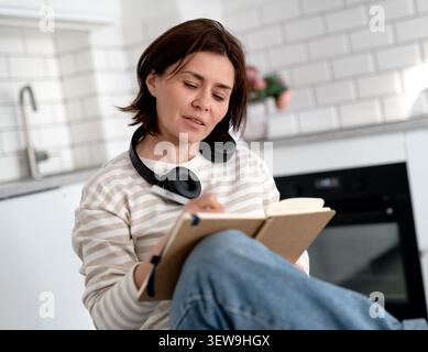 Young Woman Writes In Notebook At Home Stock Photo