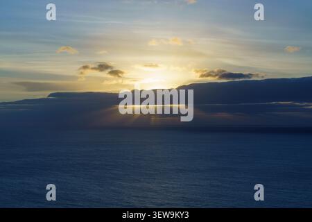 Sunset over the Atlantic Ocean, Madeira Portugal, with golden sun rays breaking through dramatic clouds above the sea. Stock Photo